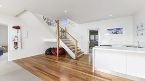 A modern kitchen with white cabinetry, a wooden staircase, and a view of the outdoors. - Bayview - Fantastic Panoramic Views of Guichen Bay - Pet Friendly Inside (Robe)