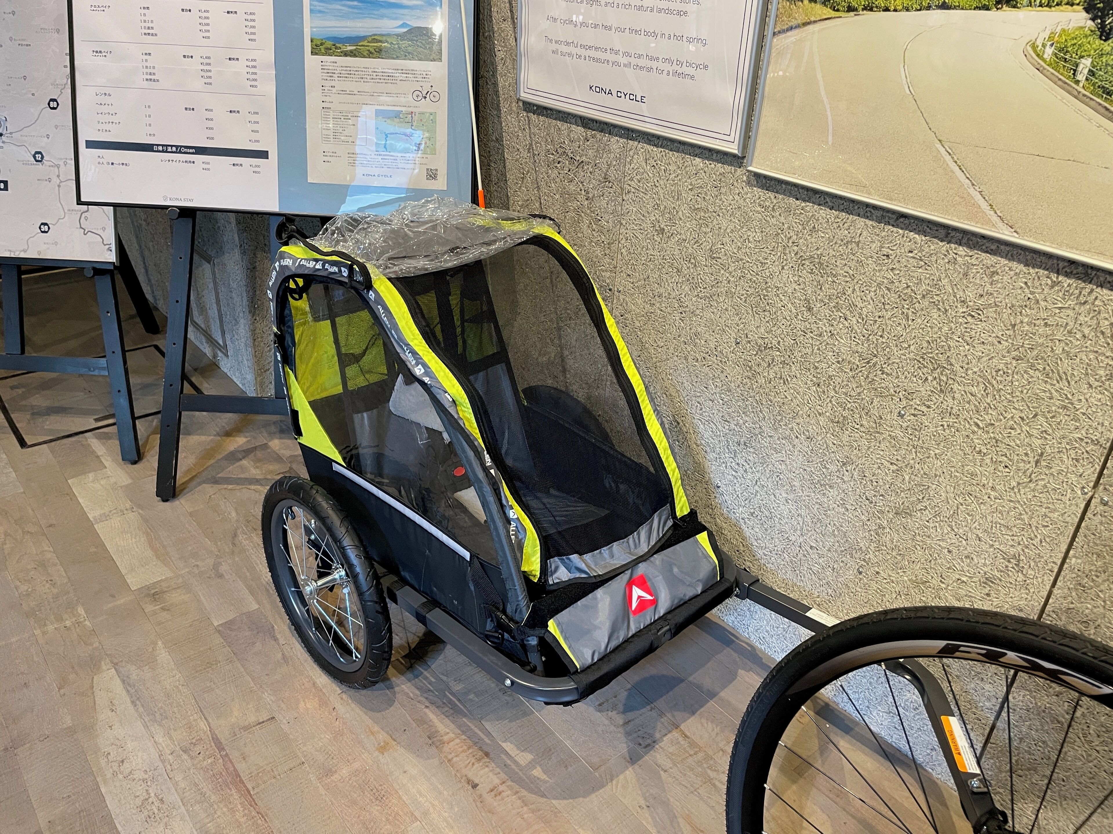 Una bicicleta pequeña y cerrada con asiento de seguridad, un mapa y un cartel sobre una ruta ciclista.