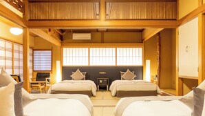 Una habitación japonesa tradicional con dos camas, un escritorio pequeño y un panel corredizo shoji.