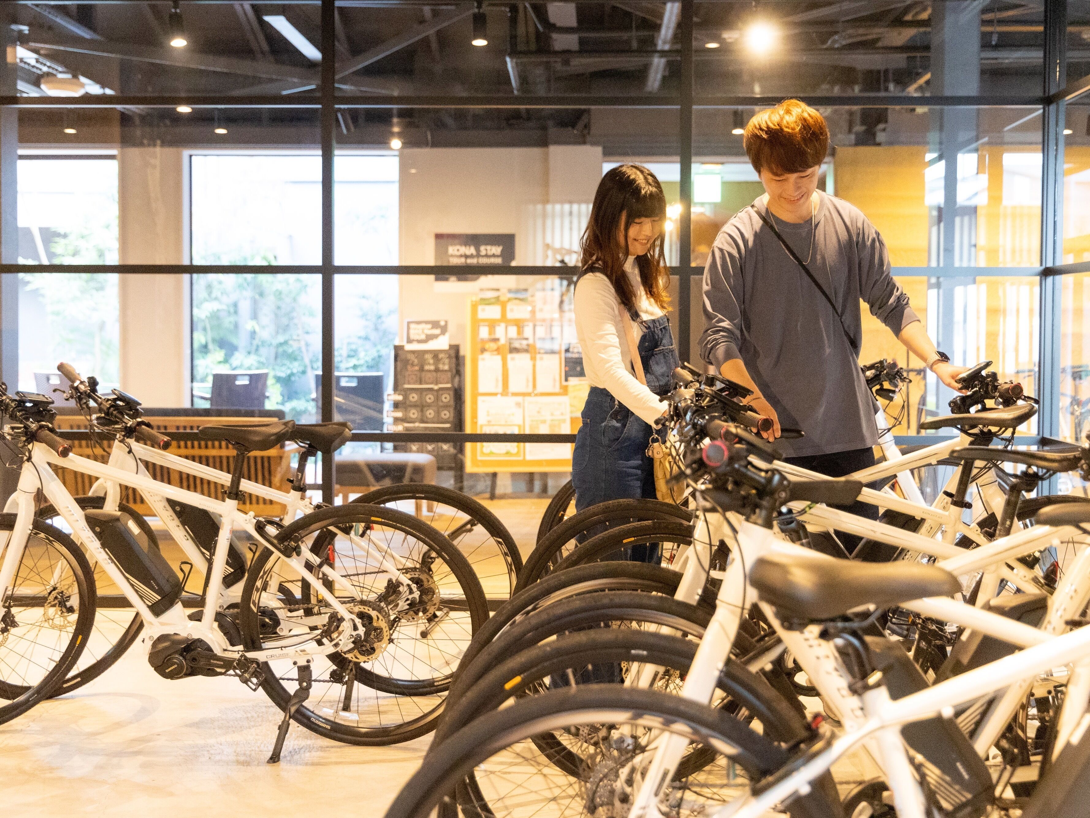 A bicycle rental station with multiple bicycles and a sign that reads "KONA STAY YOUR and OURS".