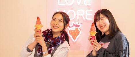 Dos personas sostienen helados frente a un letrero de neón que dice "LOVE MORE".