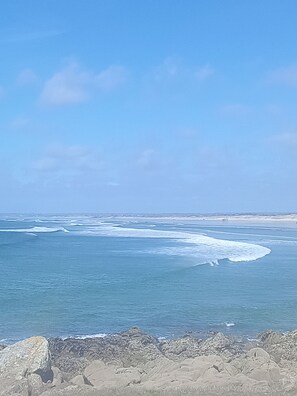 Paisagem costeira com um litoral rochoso e mar calmo.