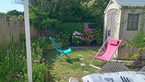 A covered patio with a table and chairs, a wooden deck, a garden with flowers and a play structure. - Independent studio + enclosed garden in Penmarc'h. Plage du Ster 800m away, laTorche 5 kms away (Penmarch)