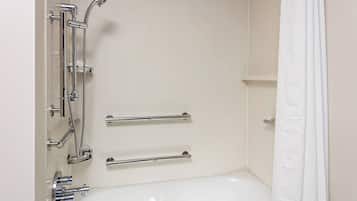 A bathroom with a white bathtub, chrome fixtures, and grab bars.