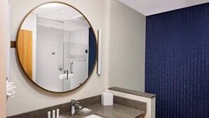 A modern bathroom with a round mirror, a sink, and a towel dispenser. - Fairfield by Marriott Port Clinton Waterfront (Port Clinton)