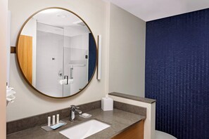 Un baño moderno con un espejo redondo, un lavabo y un dispensador de toallas.