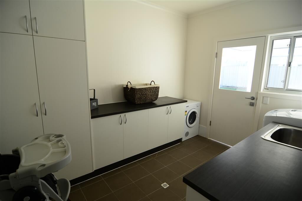 A laundry room with a washing machine, a basket, and a sink.