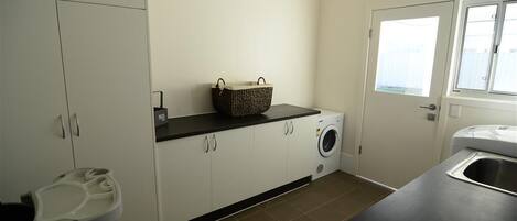 A laundry room with a washing machine, a basket, and a sink.