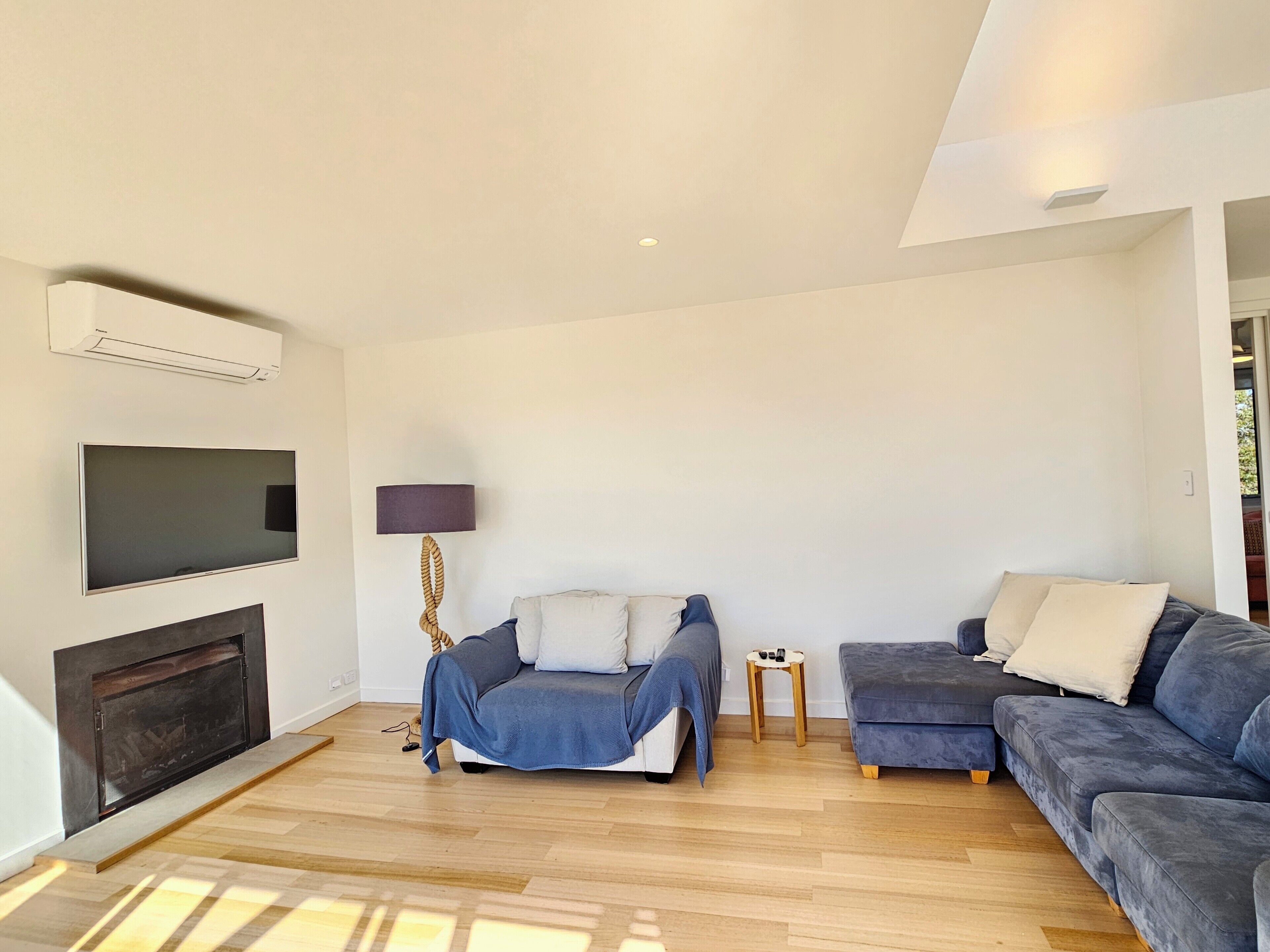 A modern living room with a flat-screen TV, a fireplace, a sofa, and a lamp.