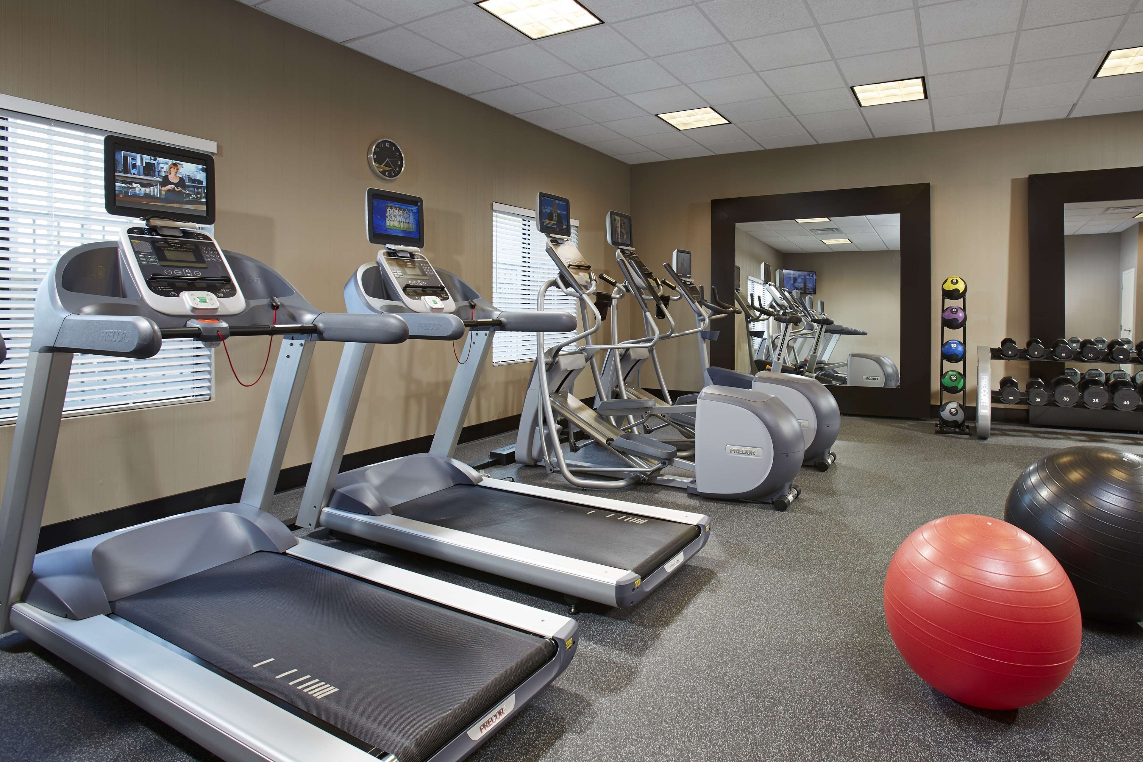 Uma academia com esteiras, elípticos e bolas de exercício.