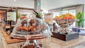 A buffet area with a variety of food items, including a covered chocolate display and a bowl of fruit. - Hilton Garden Inn Toronto Brampton West (Brampton)