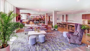 A spacious lobby with a central seating area, multiple dining tables, and a modern kitchen in the background. - Hilton Garden Inn Toronto Brampton West (Brampton)