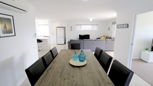Un espace repas moderne avec une table en bois, des chaises noires et un îlot central agrémenté de deux bouteilles bleues.