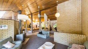 Sala de estar moderna com lareira, sofá, mesa de centro e área de jantar ao fundo.