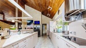 Uma cozinha moderna com armários brancos, eletrodomésticos de aço inoxidável e teto de madeira.