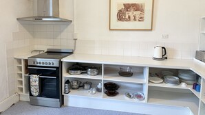 A kitchen with white cabinets, a stainless steel stove, and a hanging framed picture. - Cornerstone Cottage - Historic 1850's Cottage Pets Welcome - Inside by neg (Robe)