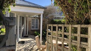 A covered patio area with a wooden fence, a wooden chair, and a table. - Cornerstone Cottage - Historic 1850's Cottage Pets Welcome - Inside by neg (Robe)