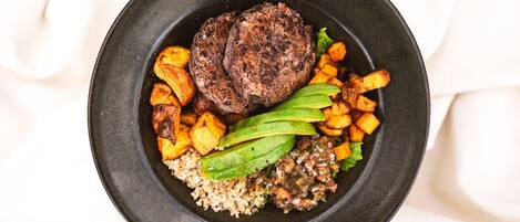 A plate with a steak, roasted potatoes, avocado, and a side of quinoa.