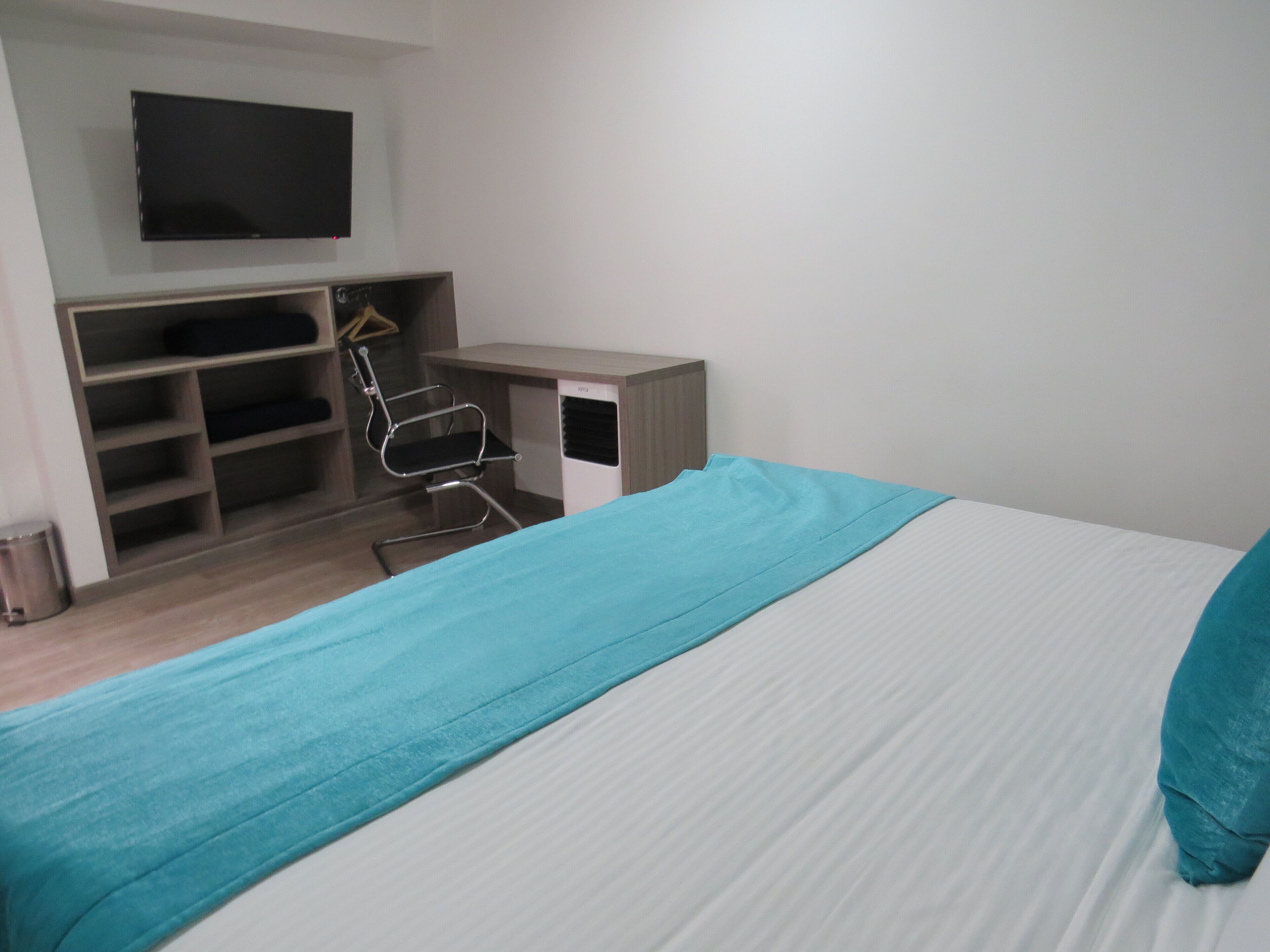 A bedroom with a bed, a desk, and a chair.