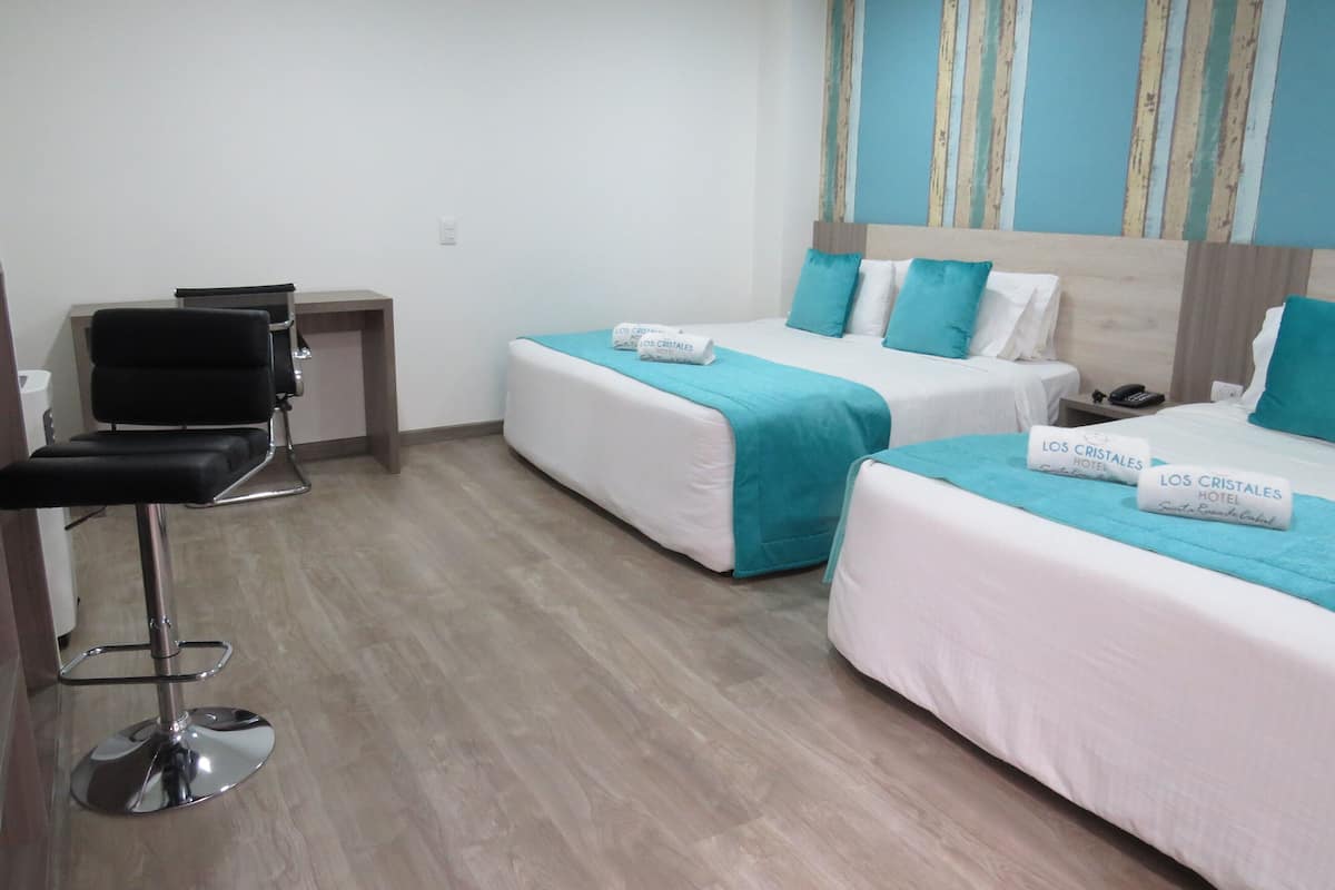 A hotel room with two beds, a desk, and a chair.