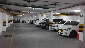 A multi-level parking garage with several cars and motorcycles parked.