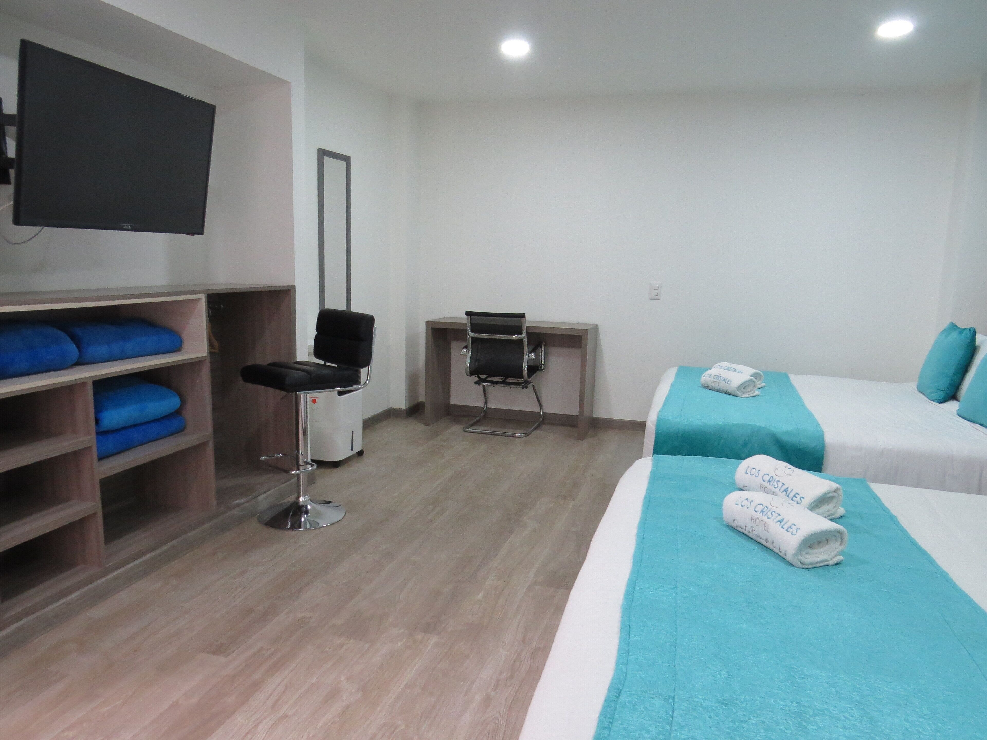 A hotel room with a bed, a desk, a chair, and a TV.
