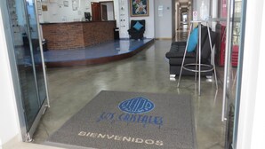 Un espace d’accueil comprenant un comptoir de réception, un canapé noir et un fauteuil bleu.
