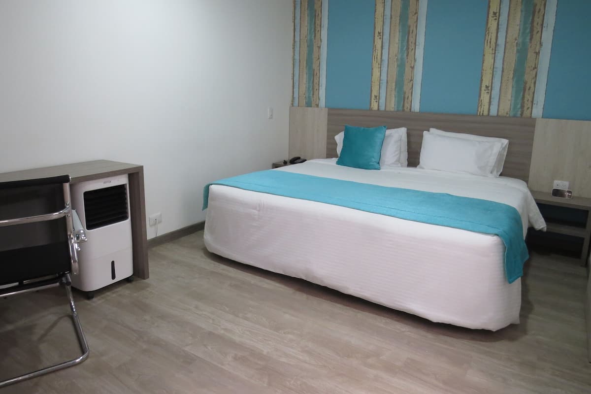 A hotel room with a bed, a desk, and a nightstand.