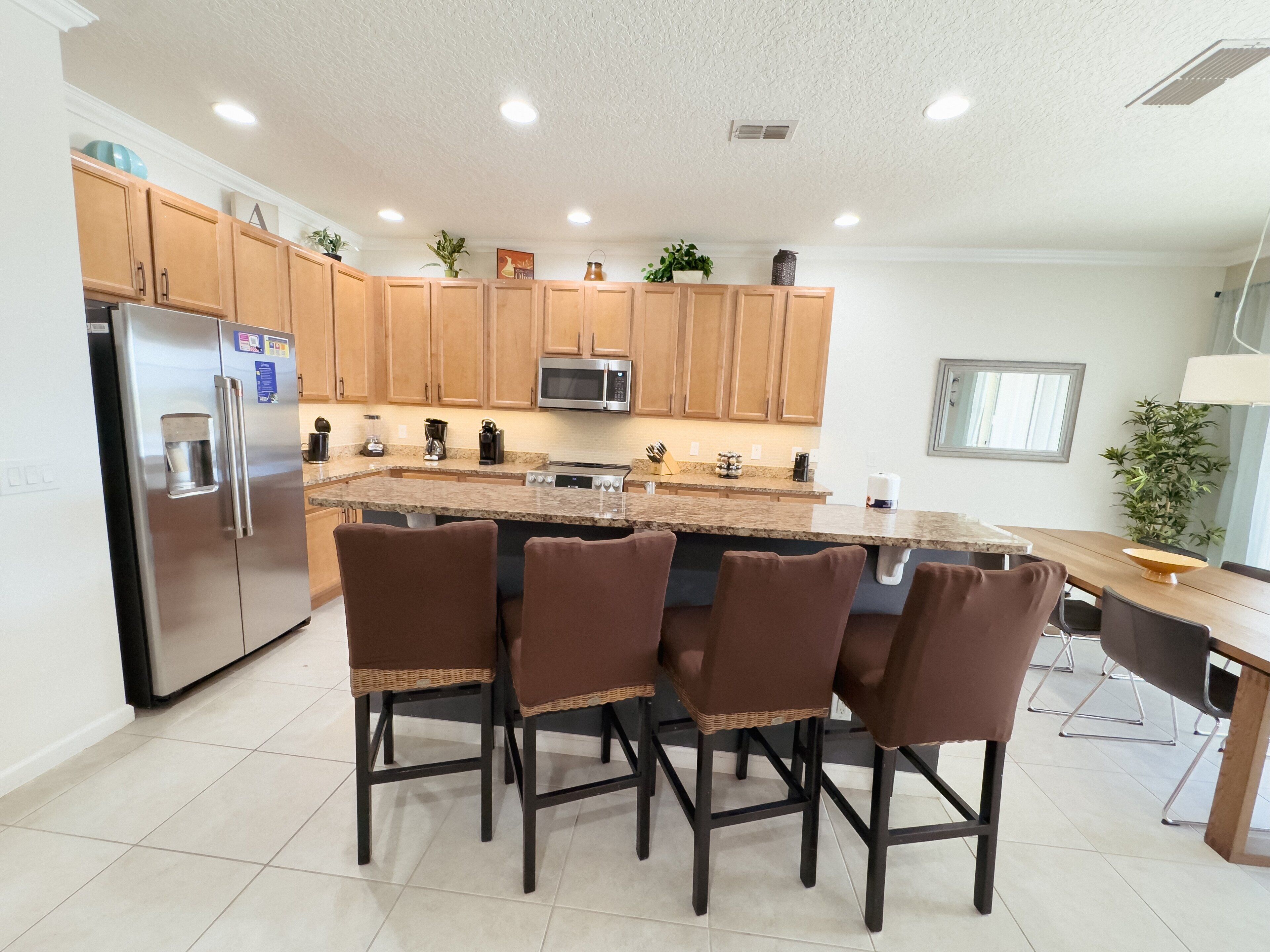 A modern kitchen with wooden cabinets, stainless steel appliances, and a central island with bar stools.