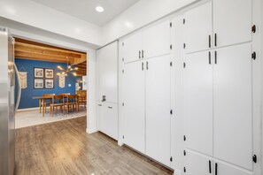 Una cucina moderna con mobili bianchi, un tavolo da pranzo in legno e una parete decorata in blu.