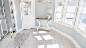 A hallway with a white door, a sign reading "BEACH HOUSE", a console table with a lamp, and a patterned rug. - 400 Yards to the Beach! Dogs Welcome! (Dennis Port)
