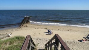 A beach with a wooden walkway leading to the shore, a rocky outcrop, and a few people relaxing on the sand. - 400 Yards to the Beach! Dogs Welcome! (Dennis Port)
