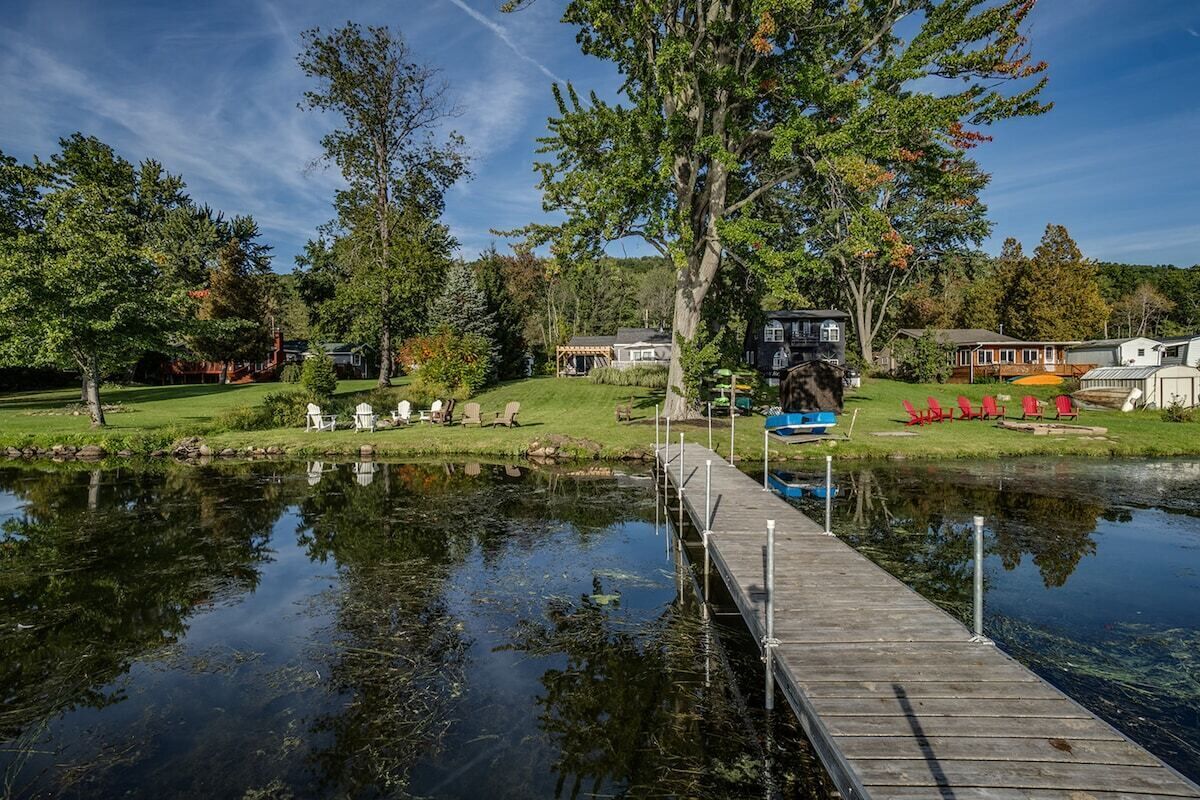 A lakeside property with a dock, a boat, and several houses in the background.