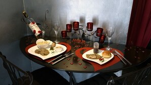A table set for two with a bottle of wine, glasses, and plates of food. - Suite Rouge Passion avec jacuzzi privatif en Provence (Plan-d'Orgon)