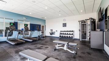A gym with treadmills, weight benches, dumbbells, and a cable machine.