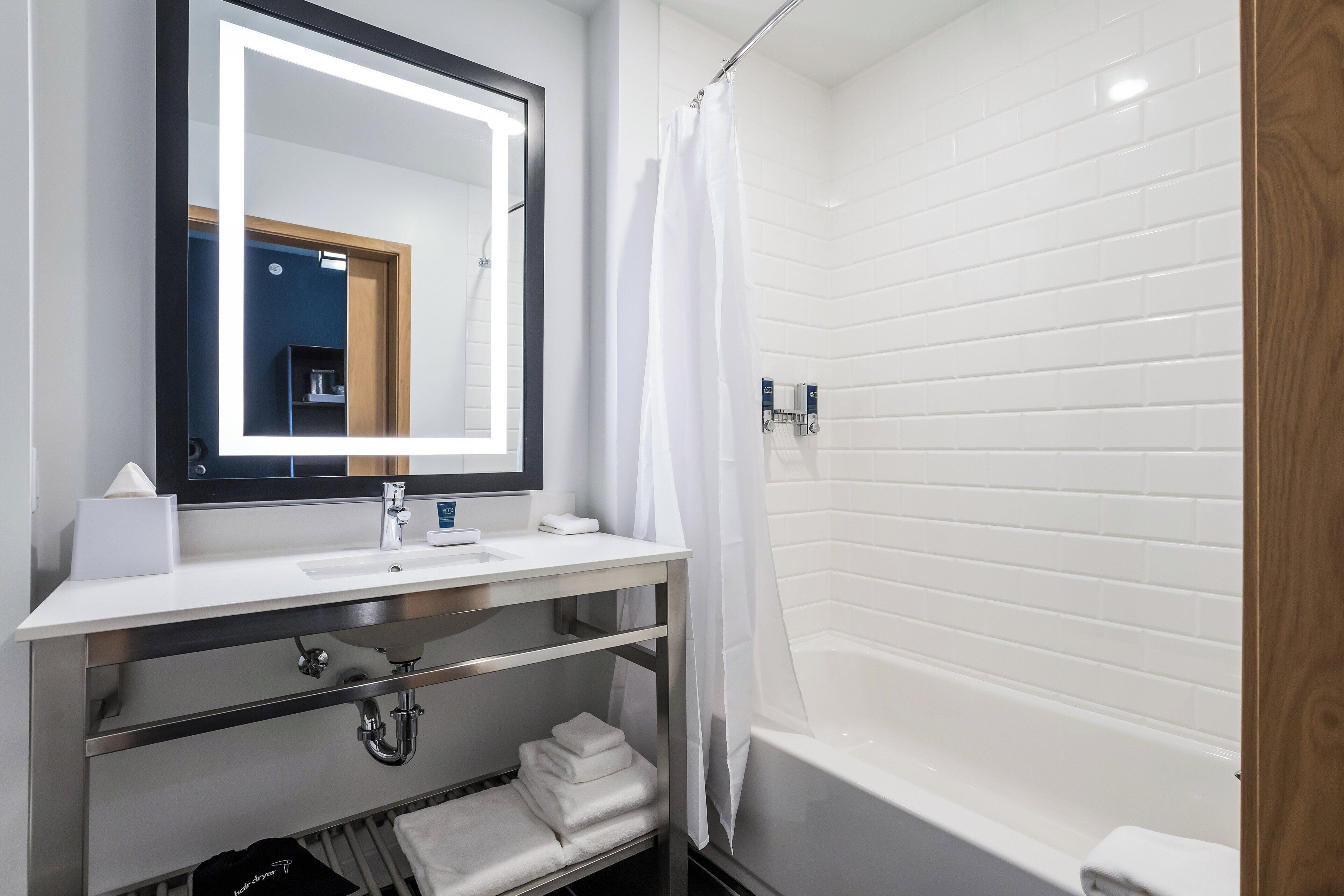 A modern bathroom with a white sink, mirror, and bathtub.