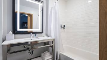A modern bathroom with a white sink, mirror, and bathtub.