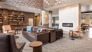 A modern lobby with leather sofas, a fireplace, and a brick-patterned ceiling.
