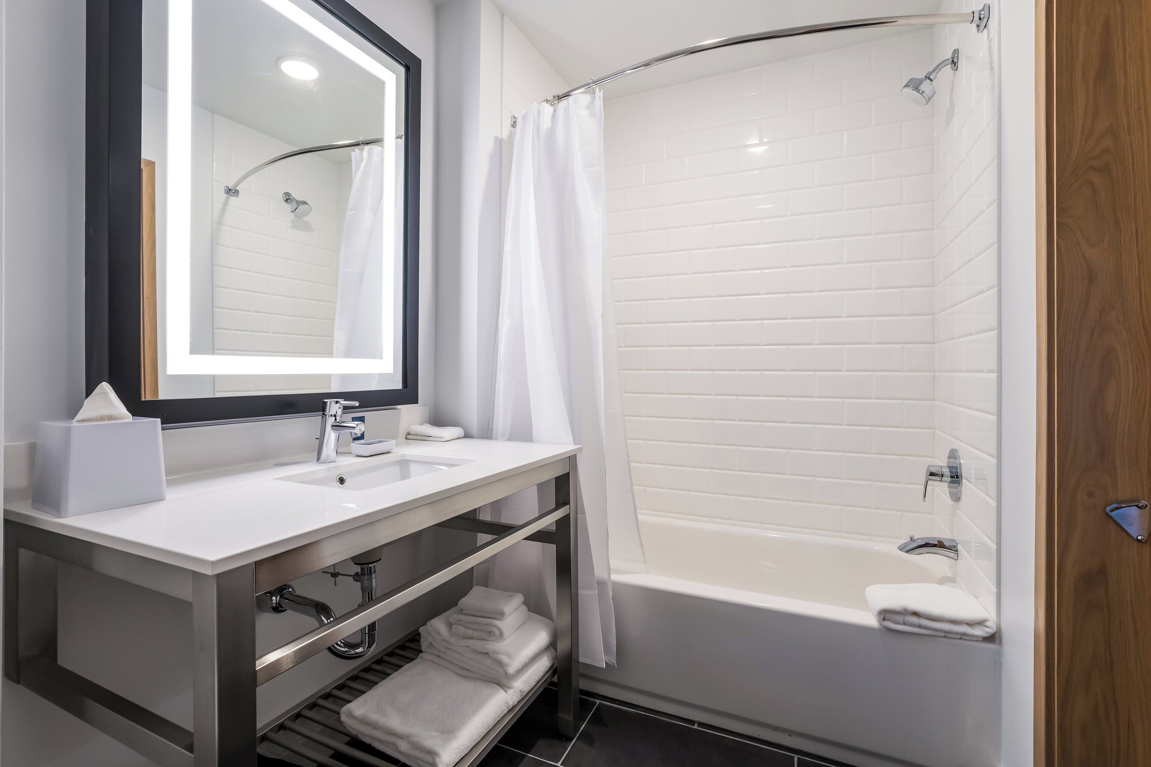 Een moderne badkamer met een wit wastafelmeubel, spiegel en douche.