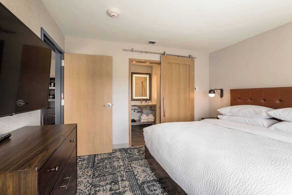 A hotel room with a bed, a wardrobe, a mirror, and a television.