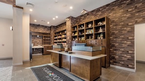 A reception area with a reception desk, wooden shelving with various items, and a stone-patterned wall.