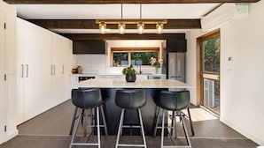 A modern kitchen with a central island, bar stools, and a window with a view.