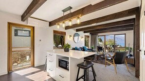 A modern kitchen with a central island, wooden beams, and large windows.