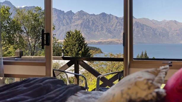 A room with a large window overlooking mountains and a body of water.
