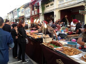 A street food market with various food stalls and people.