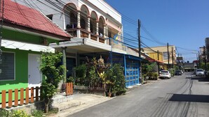 A street view with buildings, a blue gate, and parked cars. - Phuket Town Budget Lodge AirconRoom1+Washer (Phuket)