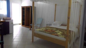 A room with a four-poster bed, a desk, a wardrobe, and a chair. - Villa Tambatra (Mahavelona)