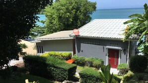 Ein Haus mit roter Tür, umgeben von gepflegten Gärten und Blick aufs Meer.