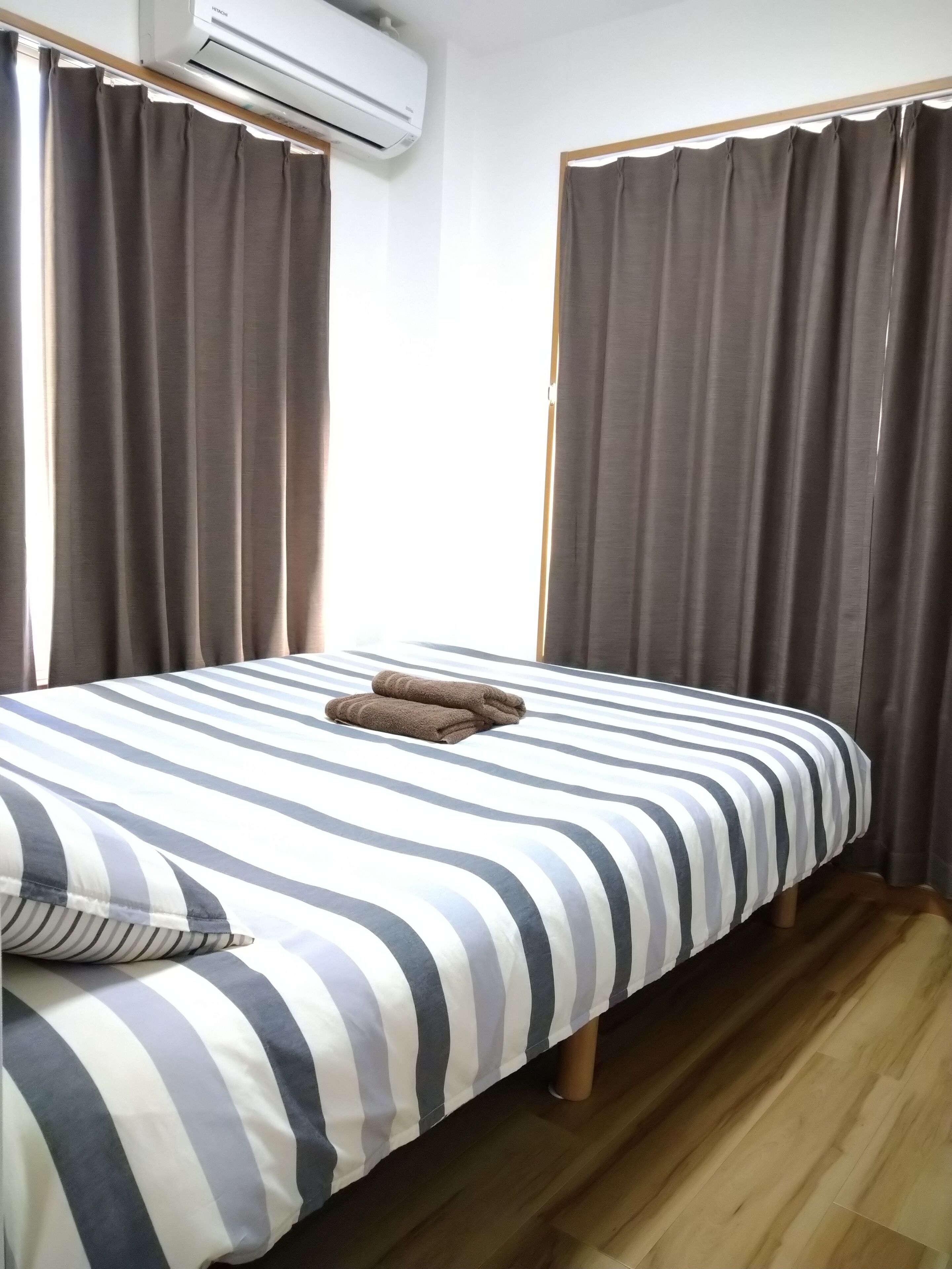 Een eenpersoonsbed met gestreept beddengoed, een opgevouwen handdoek en een kussen.