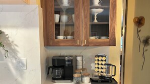 Een keuken met houten kastjes, een koffiezetapparaat, een blender en een pot met kruiden.